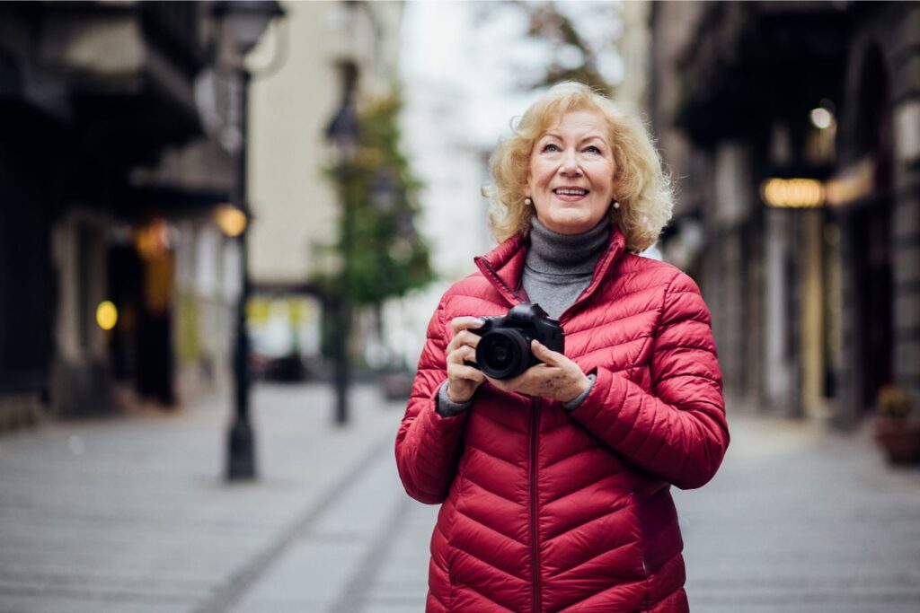žena se priprema fotografirati nešto. stoji na ulici i drži fotoaparat u rukama.